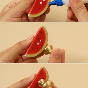 May include: Images showing the assembly of watermelon-shaped cabinet knobs. The knobs are red with black and white details, and are being attached to a brass base. The text at the bottom reads, "The installation of all knobs is done by hand."