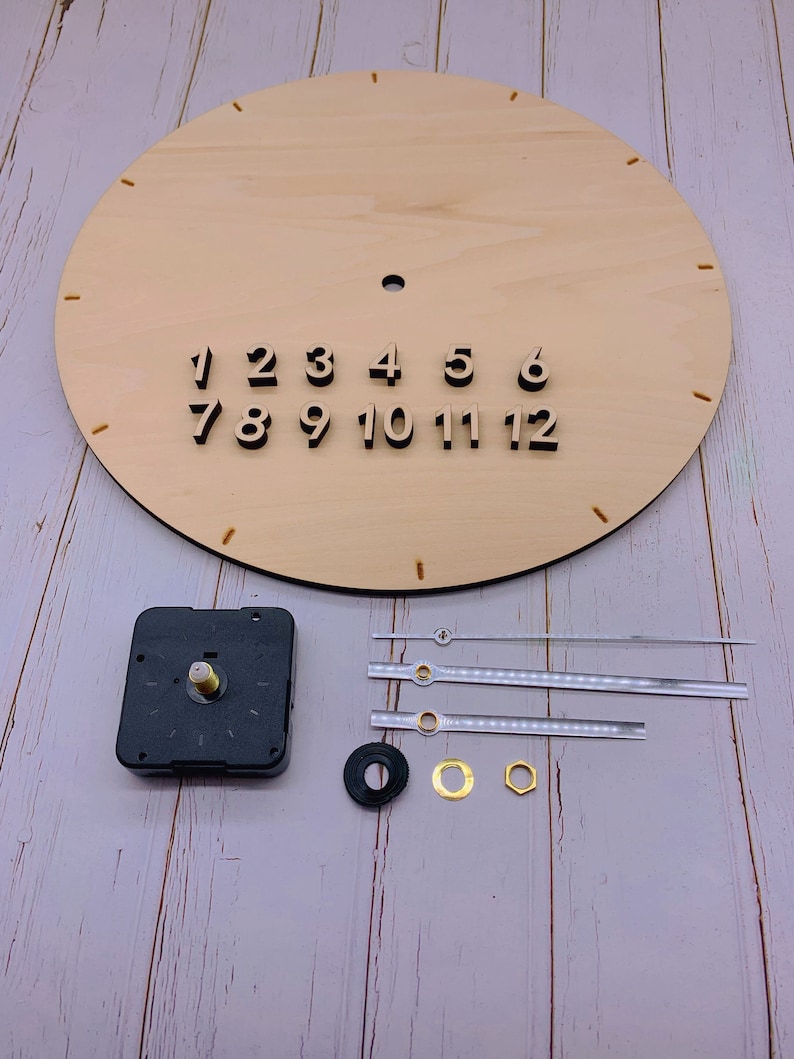 May include: A DIY clock kit with a wooden clock face, black numbers, and a black clock mechanism. The kit also includes three clear clock hands, a black washer, a gold washer, and a gold nut.