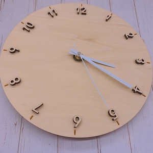 May include: A wooden clock face with black numbers 1 through 12. The clock hands are white and the clock is set to 12:00.