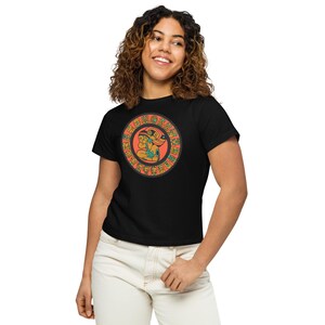 May include: Black t-shirt with a circular design featuring a stylized image of two figures in orange, green, and blue colors. The figures are surrounded by a circle of smaller figures in orange and black.