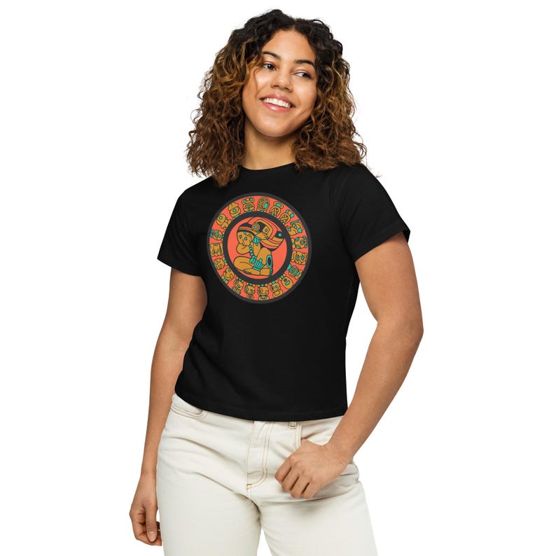 May include: Black t-shirt with a circular design featuring a stylized image of two figures in orange, green, and blue colors. The figures are surrounded by a circle of smaller figures in orange and black.