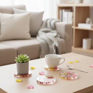 May include: A cozy living room scene featuring a wooden coffee table with a cup of tea, a small succulent in a gray pot, and several decorative coasters. The coasters have a clear resin design with colorful floral inclusions.