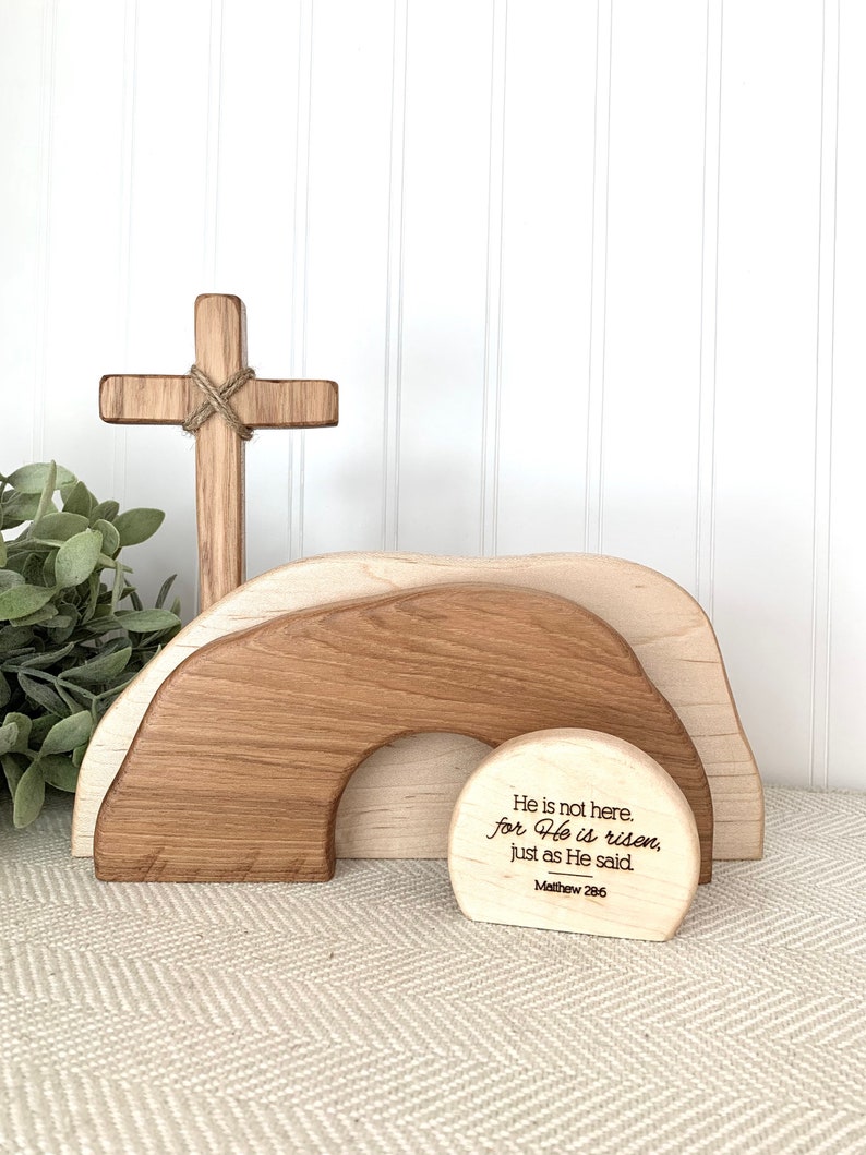 May include: Wooden Easter decor with a cross, a tomb, and a round sign with the text "He is not here. for He is risen, just as He said. Matthew 28:6".