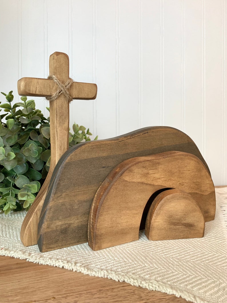 May include: Wooden Easter tomb with a cross, the tomb is made of three pieces that fit together, the cross is tied with twine.