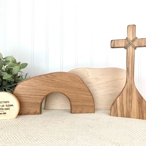 May include: Wooden Easter set with a cross, a tomb, and a sign with the text "He is not here. for He is risen Just as He said Matthew 28:6".