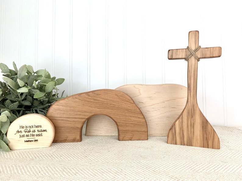 May include: Wooden Easter set with a cross, a tomb, and a sign with the text "He is not here. for He is risen Just as He said Matthew 28:6".