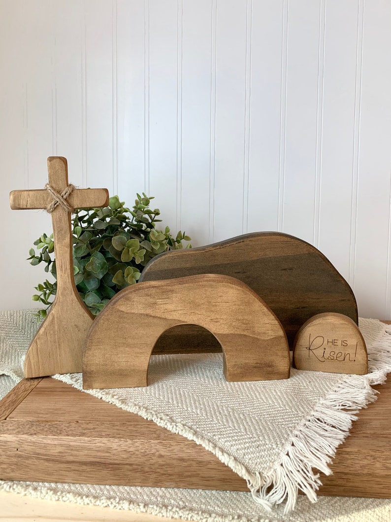 May include: Wooden Easter set with a cross, a tomb, and a stone with the text "He is Risen!" The set is made of natural wood and has a rustic finish.