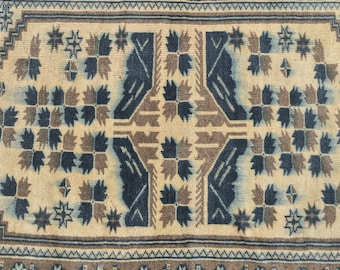 May include: A beige rug with a geometric pattern in shades of brown and blue. The pattern features stylised leaves and stars.