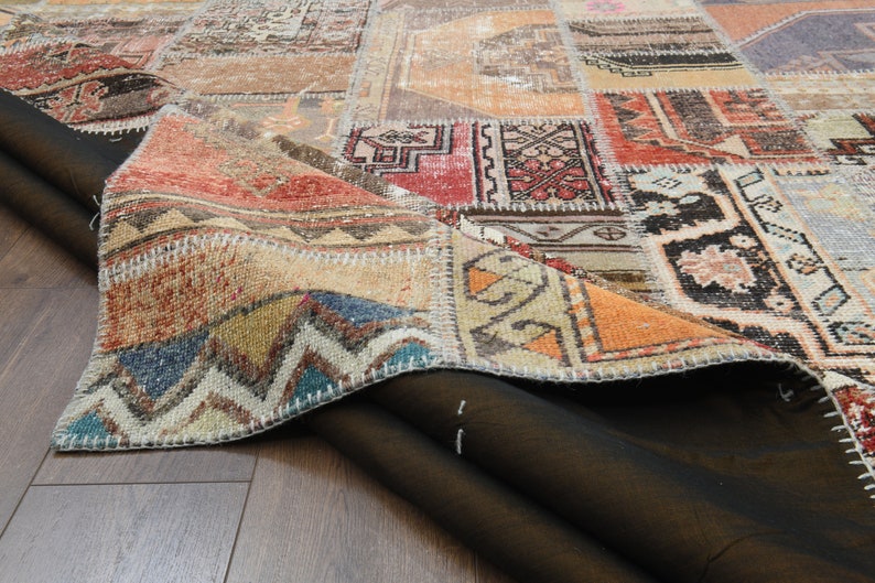 May include: A close-up of a colorful patchwork rug with a variety of patterns and colors, including red, blue, green, and yellow. The rug is folded in half, revealing the underside of the fabric.
