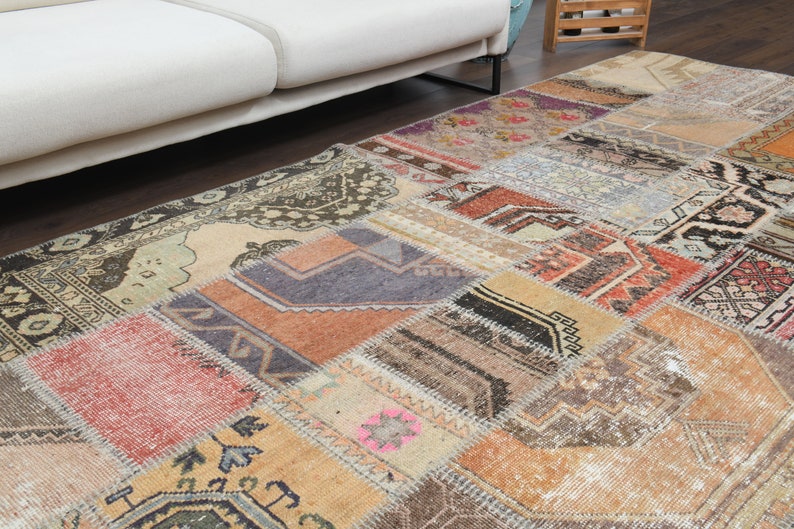 May include: A patchwork rug with a variety of colors and patterns, including brown, beige, red, and blue. The rug is made of different pieces of fabric that have been sewn together.