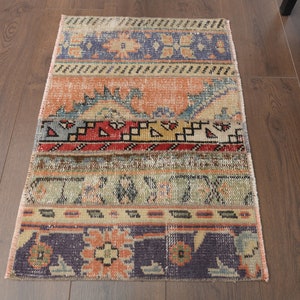 Könnte beinhalten: Ein bunter Vintage-Teppich mit einem geometrischen Muster in Blautönen, Rot, Gelb und Orange. Der Teppich hat einen abgenutzten Look und ist aus gewebtem Stoff.