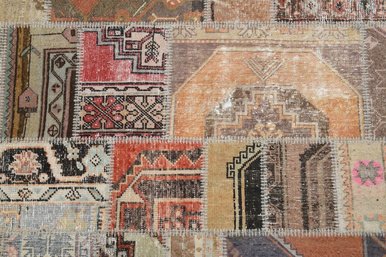 May include: A patchwork rug made of different pieces of fabric with intricate patterns in shades of brown, beige, red, and blue. The rug has a worn and vintage look.