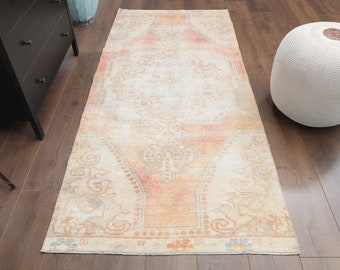 May include: A vintage-style rug with a faded floral pattern in shades of peach, cream, and beige. The rug has a distressed look and is perfect for adding a touch of bohemian charm to any room.