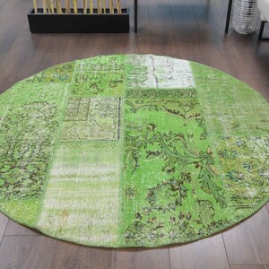 Könnte beinhalten: Ein runder Patchwork-Teppich in Grün und Weiß mit floralem Muster. Der Teppich ist aus recycelten Materialien hergestellt und hat einen Used-Look.