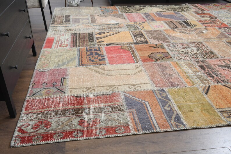May include: A patchwork rug with a variety of colors and patterns, including red, orange, brown, and beige. The rug is made of different pieces of fabric that have been sewn together.