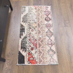 May include: A vintage-style rug with a geometric pattern in shades of red, black, white, and beige. The rug has a distressed look and is perfect for adding a touch of bohemian style to any room.