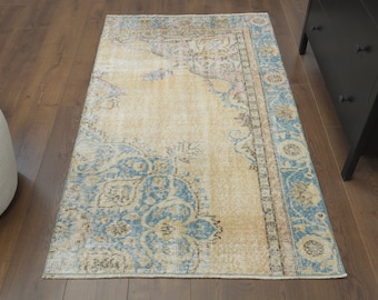 May include: A vintage rug with a light beige background and a blue and brown floral pattern. The rug has a faded, distressed look, giving it a unique and antique feel.
