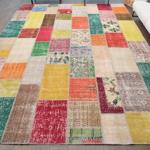 K&ouml;nnte beinhalten: Ein gro&szlig;er, rechteckiger Patchwork-Teppich mit einer lebendigen Mischung aus Farben und Mustern. Der Teppich weist eine Vielzahl von rechteckigen und quadratischen Flicken in Rot-, Orange-, Gr&uuml;n-, Gelb- und Beiget&ouml;nen auf und schafft ein einzigartiges und vielseitiges Design.