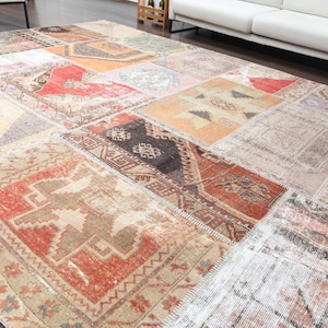 May include: A large, rectangular patchwork rug with a variety of patterns and colours. The rug features a mix of geometric and floral designs in shades of red, orange, brown, and beige. The rug is made of multiple rectangular pieces.