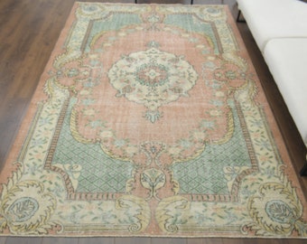 May include: A vintage rug with a pink, green, and cream color scheme. The rug has a floral pattern with a central medallion.
