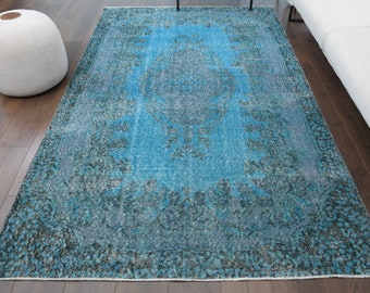 Puede incluir: Una alfombra vintage azul y negra con un patrón floral descolorido. La alfombra tiene un aspecto desgastado y es perfecta para añadir un toque de estilo bohemio a cualquier habitación.