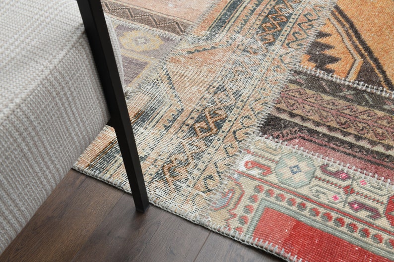 May include: A patchwork rug with different colored patterns and textures. The rug is made of various pieces of fabric sewn together. The rug is a mix of beige, brown, red, and orange colors.