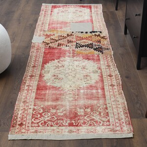 May include: A red and cream vintage rug with a floral pattern and a central medallion. The rug has a distressed look and is made of wool.