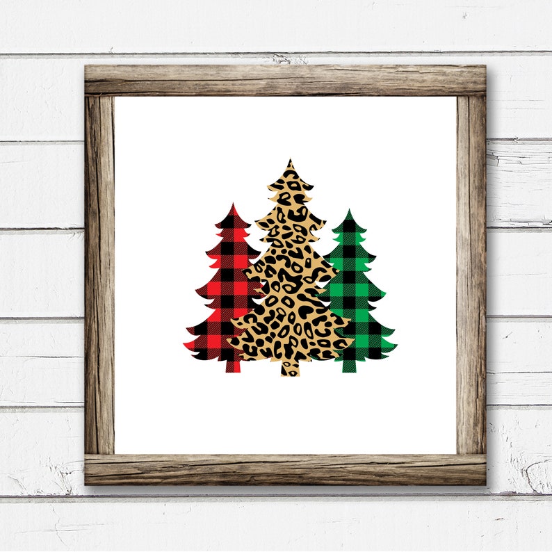 May include: Three Christmas trees in a wood frame. The center tree is leopard print, the left tree is red and black buffalo plaid, and the right tree is green and black buffalo plaid.