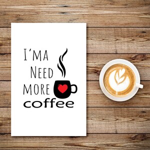 Könnte beinhalten: Weiße Karte mit schwarzem Text, der "I'm a need more coffee" lautet, mit einer schwarzen Kaffeetasse mit einem roten Herzen und Dampf, der aus der Oberseite kommt. Im Hintergrund befindet sich eine Tasse Kaffee mit Latte Art.