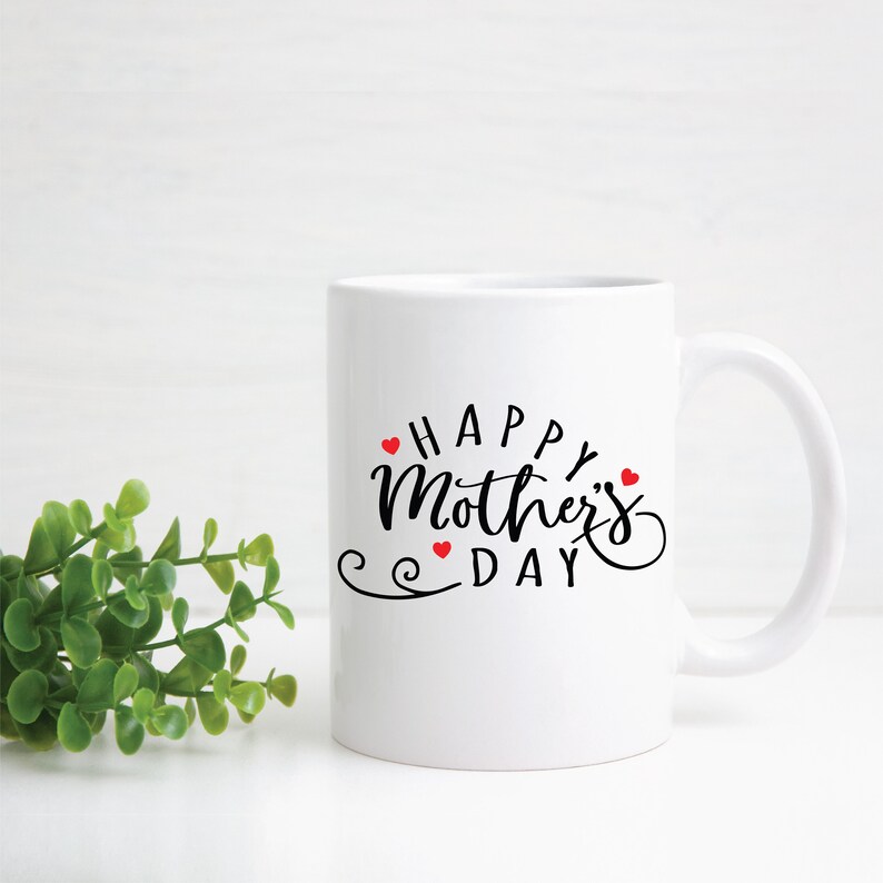 May include: White ceramic coffee mug with a black cursive inscription that reads "Happy Mother's Day" with small red hearts surrounding the text.