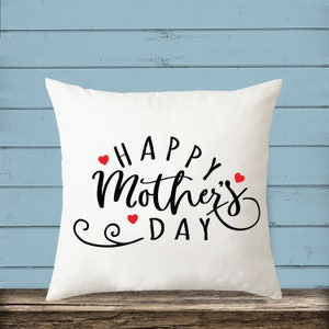 May include: White throw pillow with the text "Happy Mother's Day" in black script lettering and three red hearts.