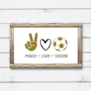 May include: A framed print with the text "Peace Love Soccer" in black lettering. The print features a gold peace sign, a gold heart, and a gold soccer ball.