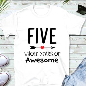 Może przedstawiać: Biała koszulka z czarnym napisem "FIVE WHOLE YEARS OF Awesome" z czarną strzałką i czerwonym sercem.