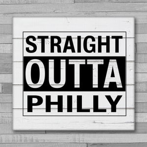 May include: Black and white sign with the text "STRAIGHT OUTTA PHILLY" on a white wood background.