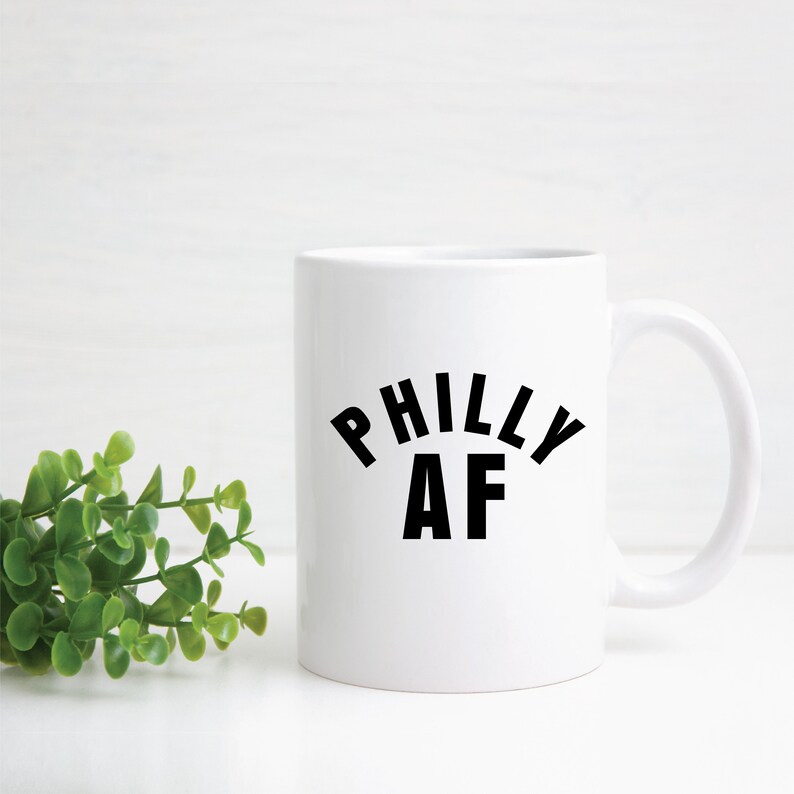 Puede incluir: Taza de caf&eacute; de cer&aacute;mica blanca con texto negro que dice "Philly AF".