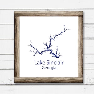 Könnte beinhalten: Ein gerahmter Druck einer blauen Umrisskarte des Lake Sinclair, Georgia. Der Text "Lake Sinclair -Georgia- " ist unter der Karte gedruckt.