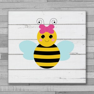 Puede incluir: Una abeja de dibujos animados linda con rayas negras y amarillas, alas azules y un lazo rosa. La abeja tiene una cara sonriente con ojos negros y mejillas rosadas.