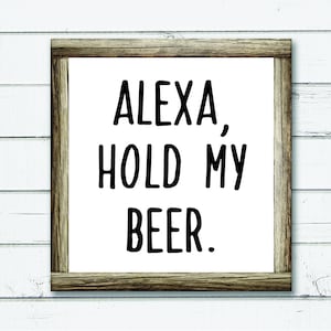 May include: A white sign with a brown wooden frame. The sign says "Alexa, hold my beer."