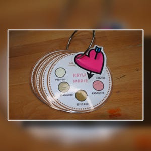 May include: A white ceramic mug with a black handle and the text "But First, Coffee" in a black, handwritten-style font. The mug is on a white surface.