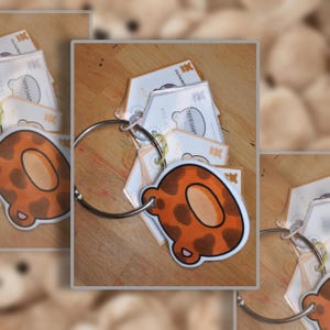 May include: A set of laminated cards held together by a silver metal ring. Each card features a cartoon illustration of a brown and orange spotted animal ear shape. The cards include printed text and small bear icons on the white background.