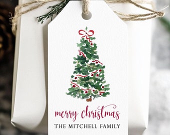 May include: A white gift tag with a watercolor illustration of a green Christmas tree decorated with red ornaments and a red ribbon. The text "merry christmas" and "THE MITCHELL FAMILY" is printed in burgundy.