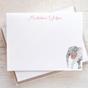 May include: White stationery with a pink floral wreath around a gray elephant. The name "Madeline Wilson" is written in pink cursive at the top.