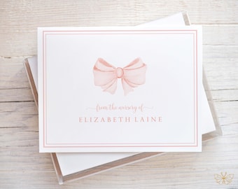 May include: A white card with a pink bow and the text "from the nursery of ELIZABETH LAINE" in a pink frame.