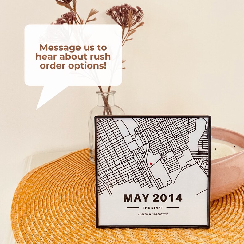May include: A black framed print of a city map with a red heart marking a location. The map is titled "MAY 2014" and includes the coordinates "42.3879 N/-83.0067" W.