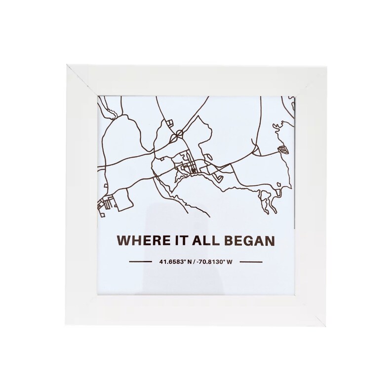 May include: White framed print with a black and white map of a city. The text "WHERE IT ALL BEGAN" is printed below the map, with the coordinates "41.6583&deg; N / 70.8130&deg; W" printed below the text.