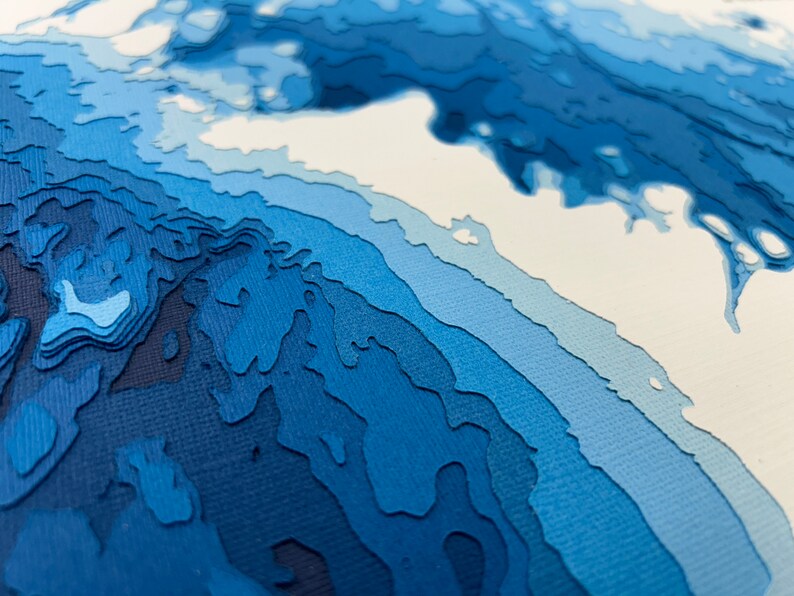 Puede incluir: Arte abstracto de papel con un esquema de color azul y blanco. El papel est&aacute; en capas y cortado para crear un efecto 3D. La obra de arte recuerda a una ola o un oc&eacute;ano.
