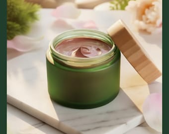 Könnte beinhalten: Ein grünes Glasgefäß mit Holzdeckel, gefüllt mit einer braunen Gesichtsmaske. Das Gefäß steht auf einer weißen Marmoroberfläche, darunter der Text "ORGANIC FACIAL MASKS". Die Szene wirkt wie ein Spa, mit sanfter Beleuchtung und floralen Elementen.