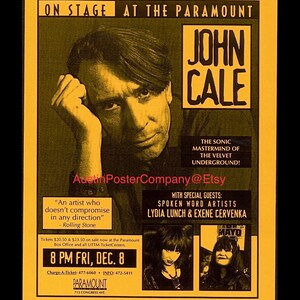May include: A vintage concert poster for John Cale at The Paramount, featuring a portrait of Cale and the text "The Sonic Mastermind of The Velvet Underground!" with special guests Lydia Lunch & Exene Cervenka. The poster is in shades of yellow and black.