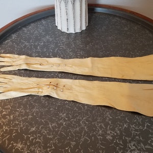 Vintage long ivory leather gloves have a faux pearl buttons hitting below the elbow.