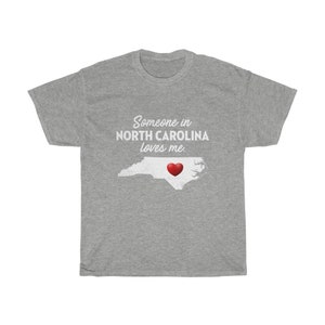 May include: Gray t-shirt with the text "Someone in NORTH CAROLINA loves me." and a red heart over an outline of the state of North Carolina.